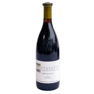 A bottle of Torbreck Barossa Valley 2018 The Factor red wine, featuring a dark glass bottle with a white label and a greenish-yellow foil capsule at the neck, set against a plain white background.