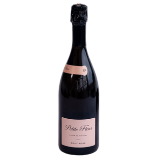 A bottle of Petite Fleur Brut Rose Champagne, featuring a dark glass bottle with a pale pink label and a black foil-wrapped neck, set against a plain white background.