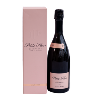 A bottle of Petite Fleur Champagne Fleur de Miraval Brut Rose stands next to its matching light pink packaging box on a clean white background.